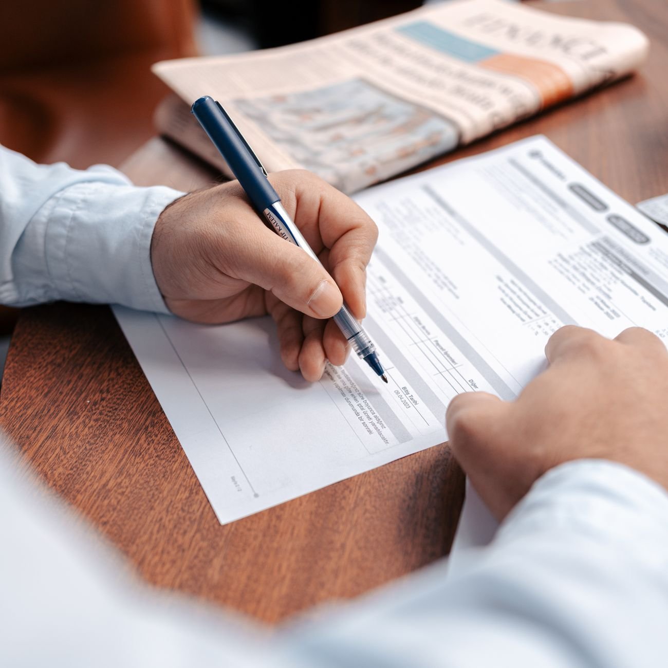 Person reviewing and writing on financial documents — the kind of admin Flowkitt bundles are built to streamline